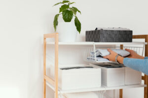 person organizes clothes on a shelf, carefully placing items for neat storage