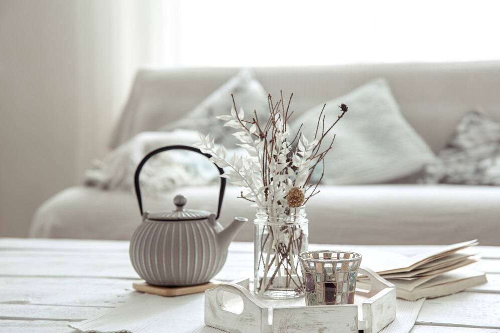 A white coffee table featuring a vase of flowers and a teapot, creating a cozy and inviting atmosphere