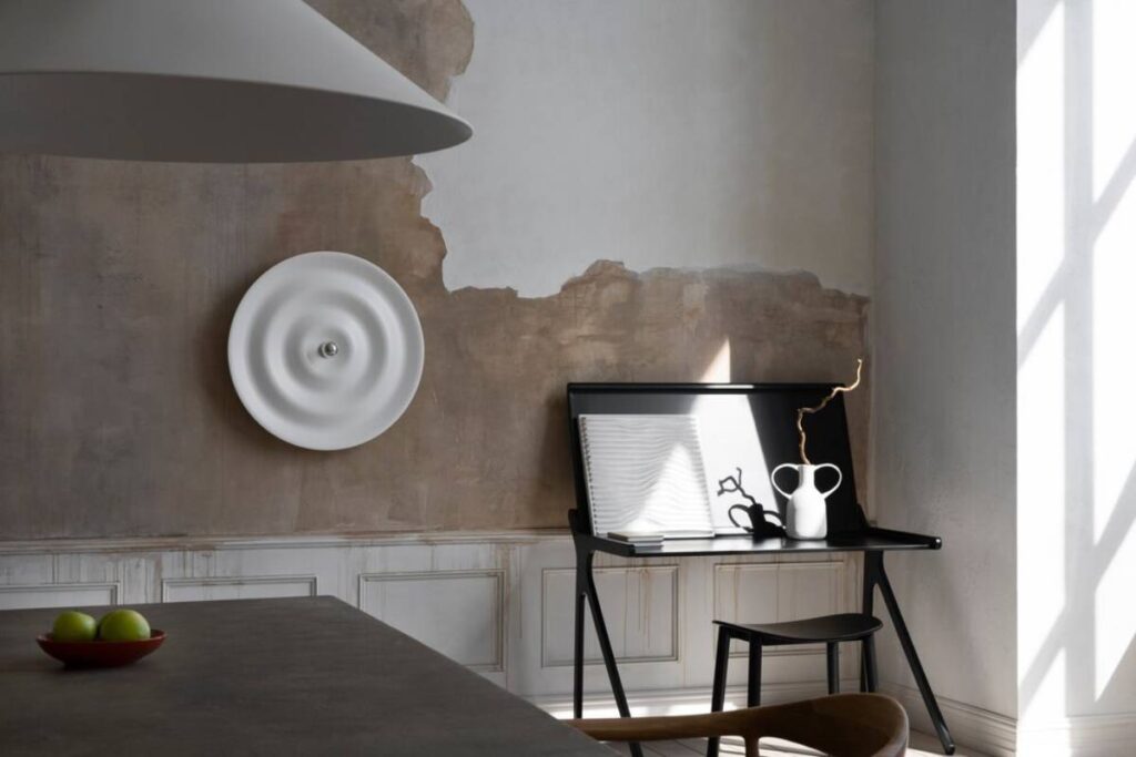 Modern minimalist styled room with designer furniture, peeling wall texture, and gentle daylight filtering through a window.