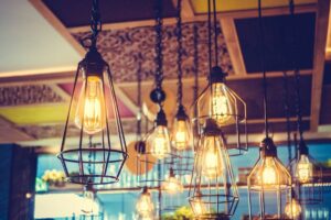 Several vintage-style pendant lights with glowing filaments hanging from a ceiling, illuminating a cozy restaurant ambiance.