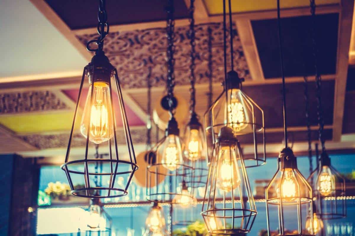 Several vintage-style pendant lights with glowing filaments hanging from a ceiling, illuminating a cozy restaurant ambiance.