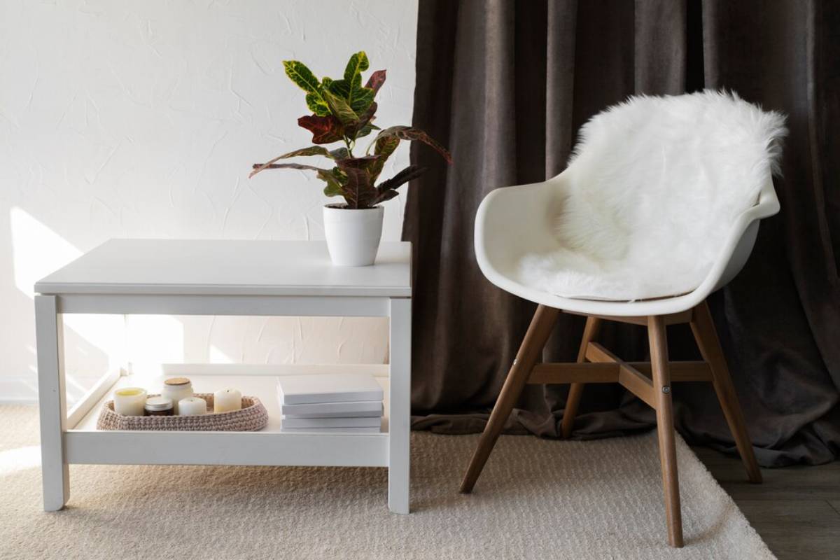 A cozy modern interior with a white table, designer chair with fur, and a potted croton plant.