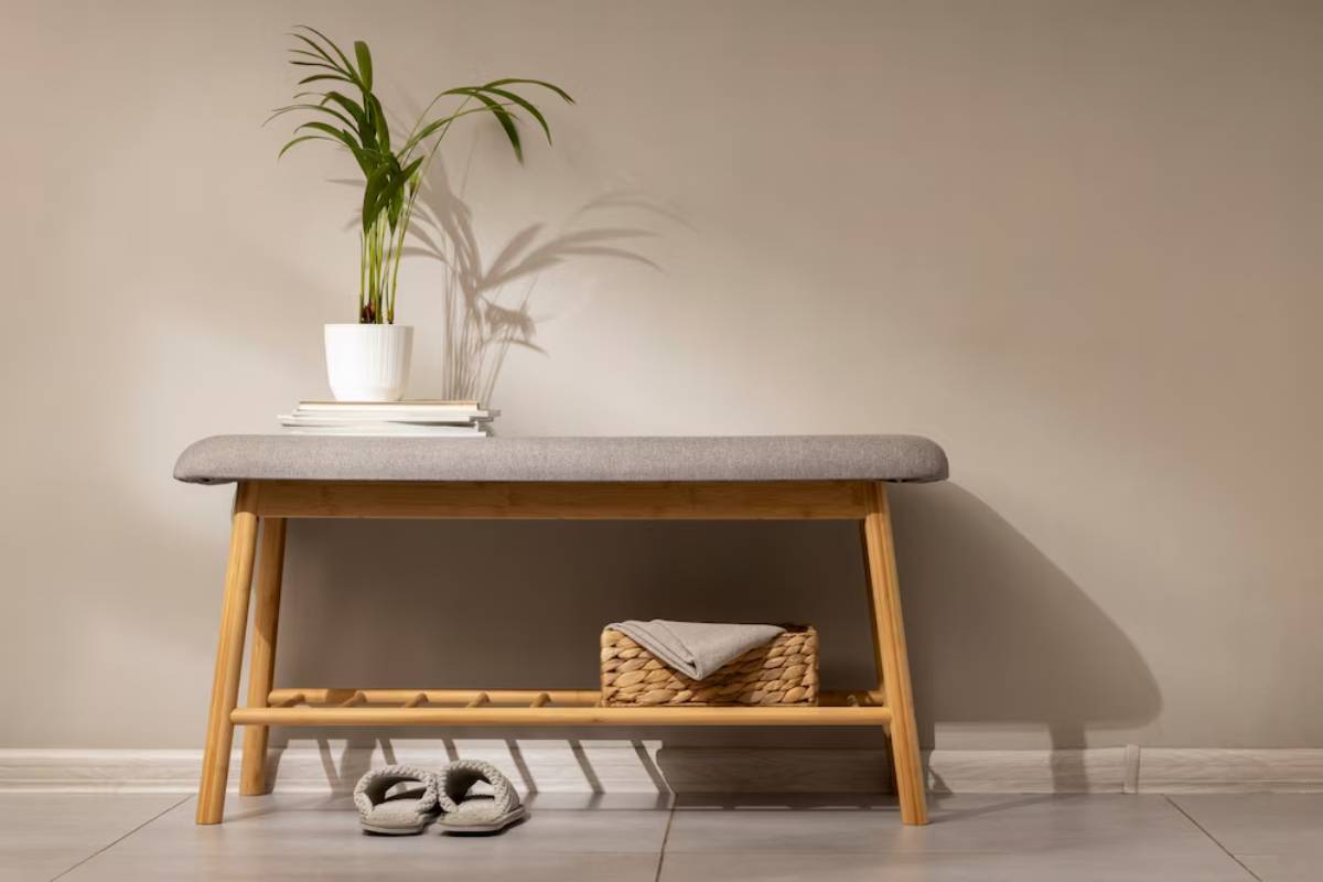 A minimalist hallway with a wooden bench, shoes beneath it, a plant, and books on top.