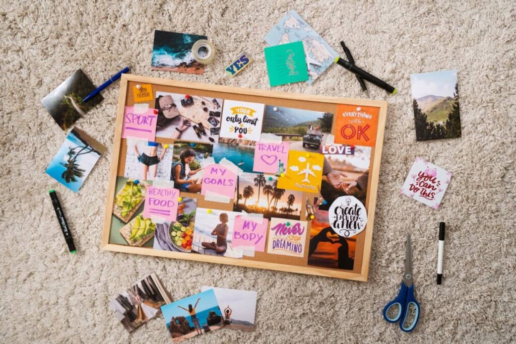 A vision board on a carpet, featuring inspirational photos and notes about fitness, travel, and personal goals. Scissors and pens are nearby.