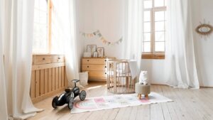 Bright and airy nursery with natural wood furniture, large windows, and playful decor.