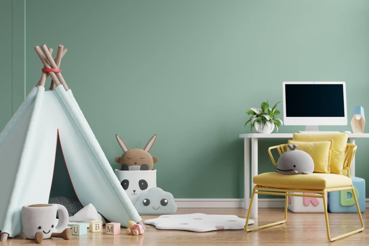 Children's room with a teal teepee, plush toys, a yellow chair, and a desk with a computer, against a light green wall.