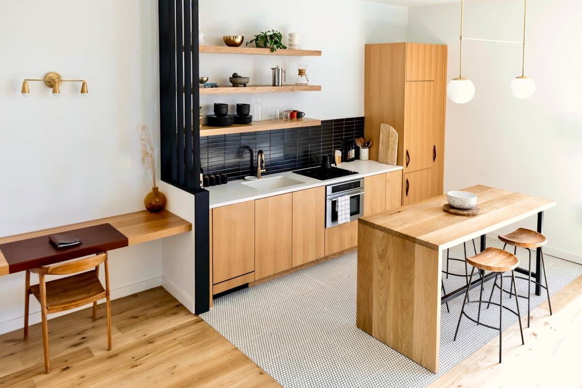 Modern kitchen with wooden cabinets, black tile backsplash, and a central island with stools.