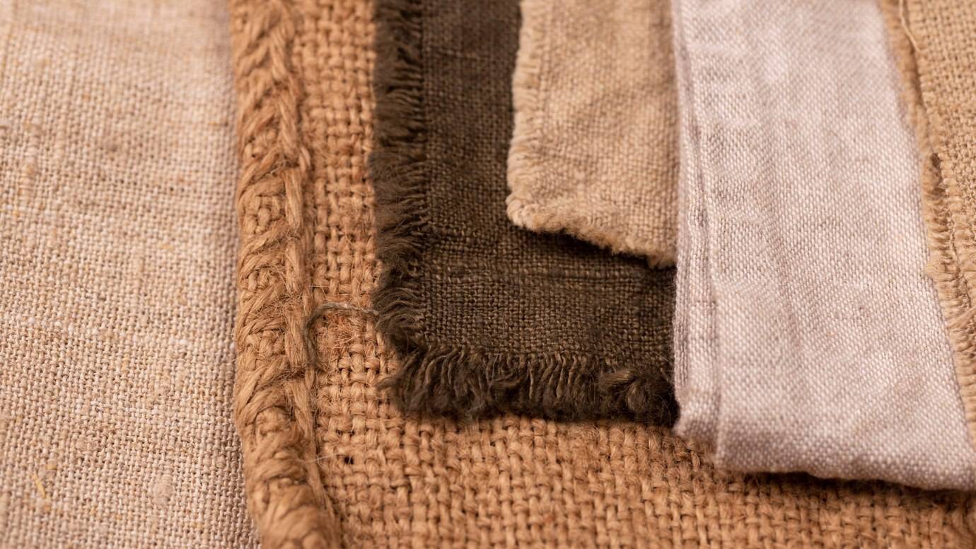 Close-up of assorted textured fabric swatches, including burlap and cotton, in earth tones.