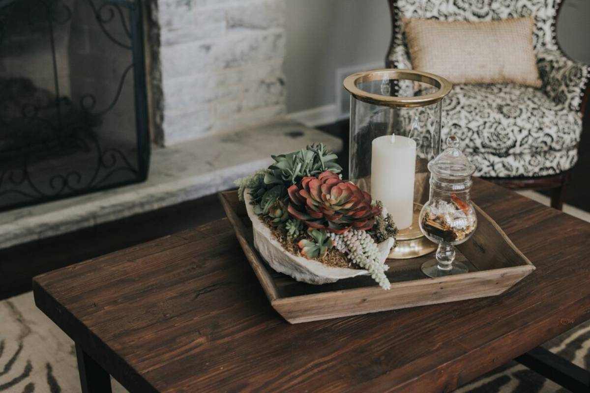 Wooden pot on a wooden table with flowers and candles on it near an armchair