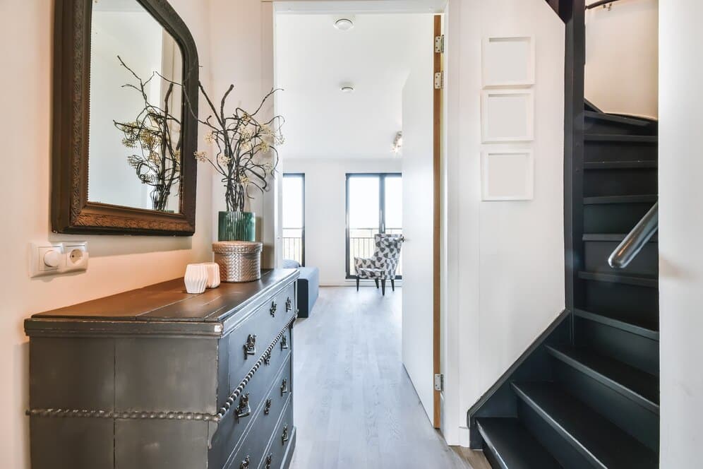 A hallway with a modern black dresser and a mirror, adding elegance and depth to the corridor.